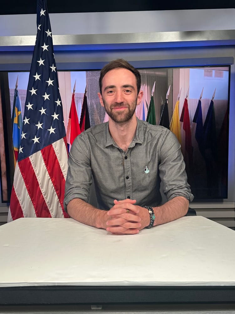 Jacob Simon smiling in front of flags